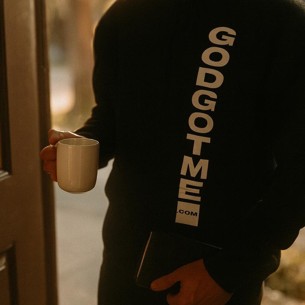 Hands serving a meal at a community kitchen, in a black GODGOTME tee